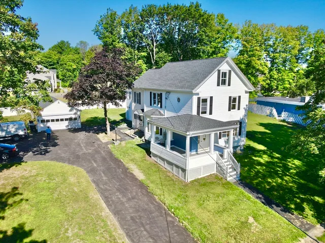 a white house with a large pool and lawn chairs under an umbrella