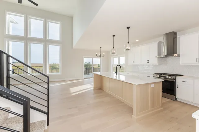 a large white kitchen with kitchen island a stove a sink and a large window