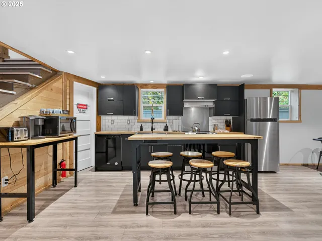a kitchen with stainless steel appliances kitchen island granite countertop a table chairs sink and cabinets