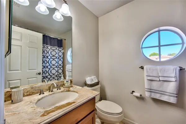 a bathroom with a granite countertop sink mirror vanity and toilet