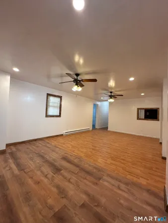 a view of a room a ceiling fan and wooden floor