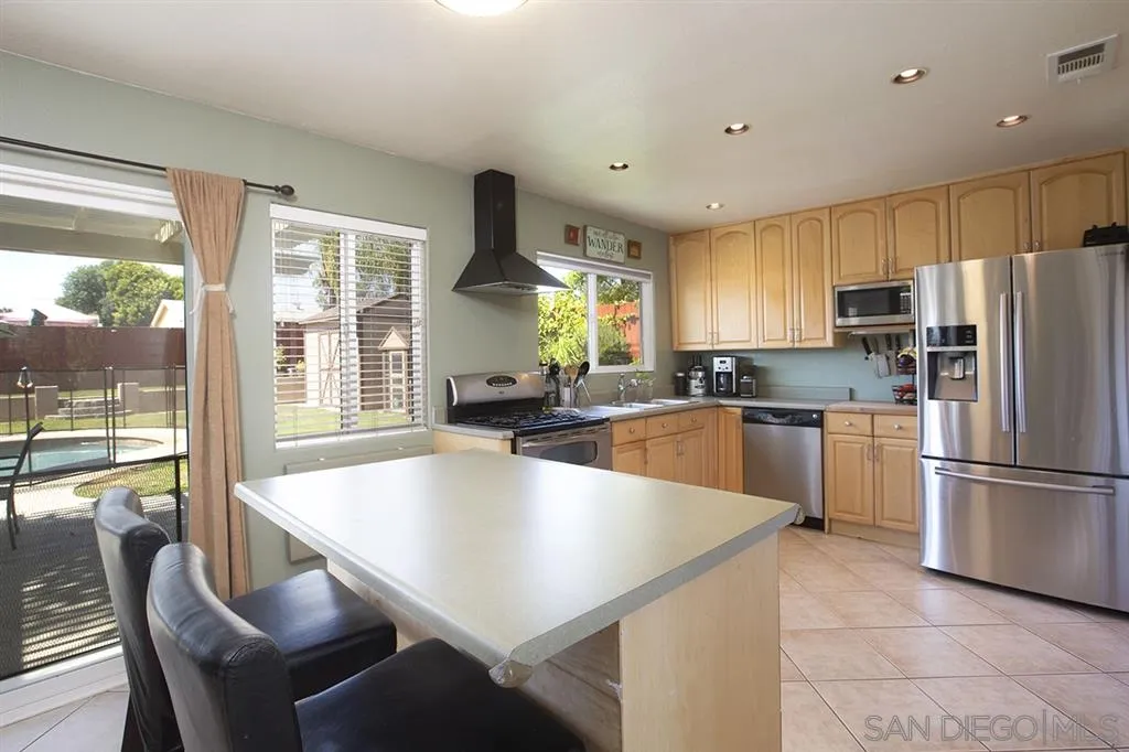 9228 Bellagio Road Santee, CA 92071 - Photo 8 of 25 a large kitchen with kitchen island a large window in it and stainless steel appliances
