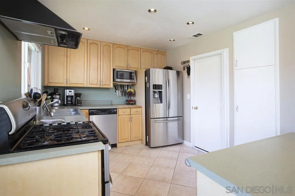 9228 Bellagio Road Santee, CA 92071 - Photo 9 of 25 a kitchen with a refrigerator a stove top oven a sink and cabinets