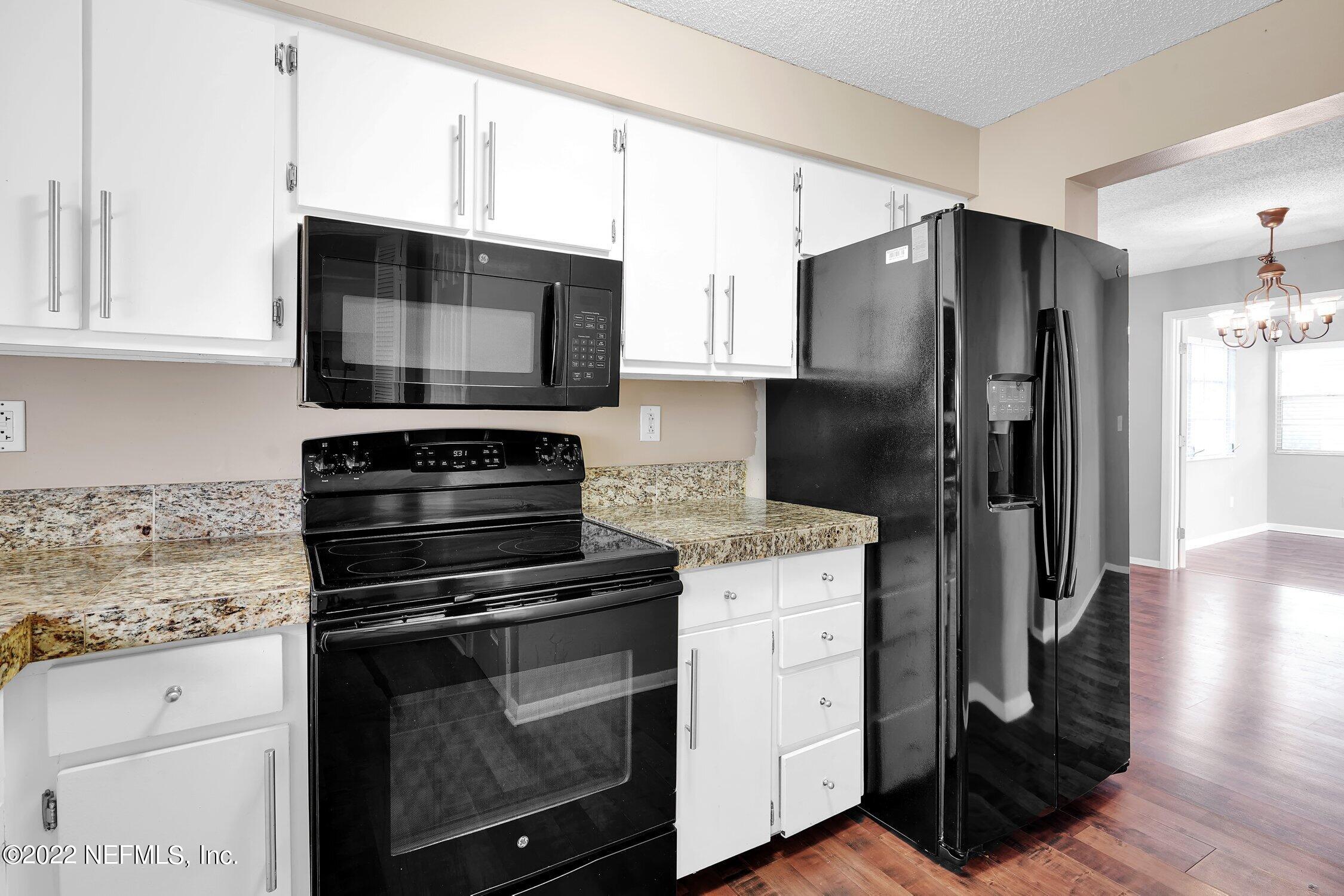 208 Baracoa Court St. Augustine, FL 32086 - Photo 19 of 32 a kitchen with granite countertop a refrigerator stove and microwave