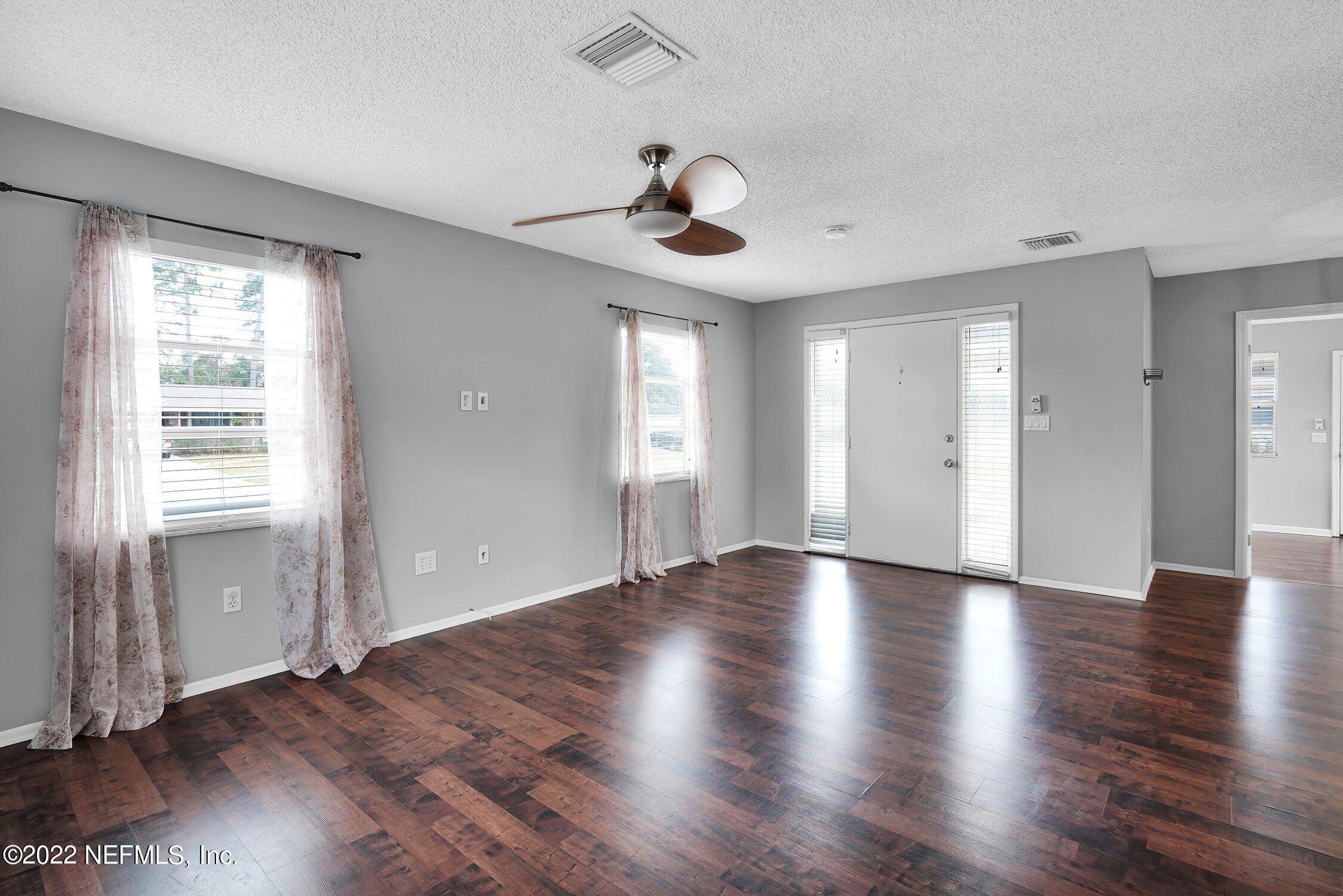 208 Baracoa Court St. Augustine, FL 32086 - Photo 8 of 32 an empty room with wooden floor chandelier fan and windows