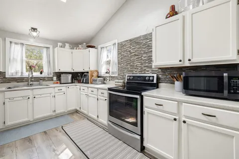 a kitchen with granite countertop white cabinets and white appliances