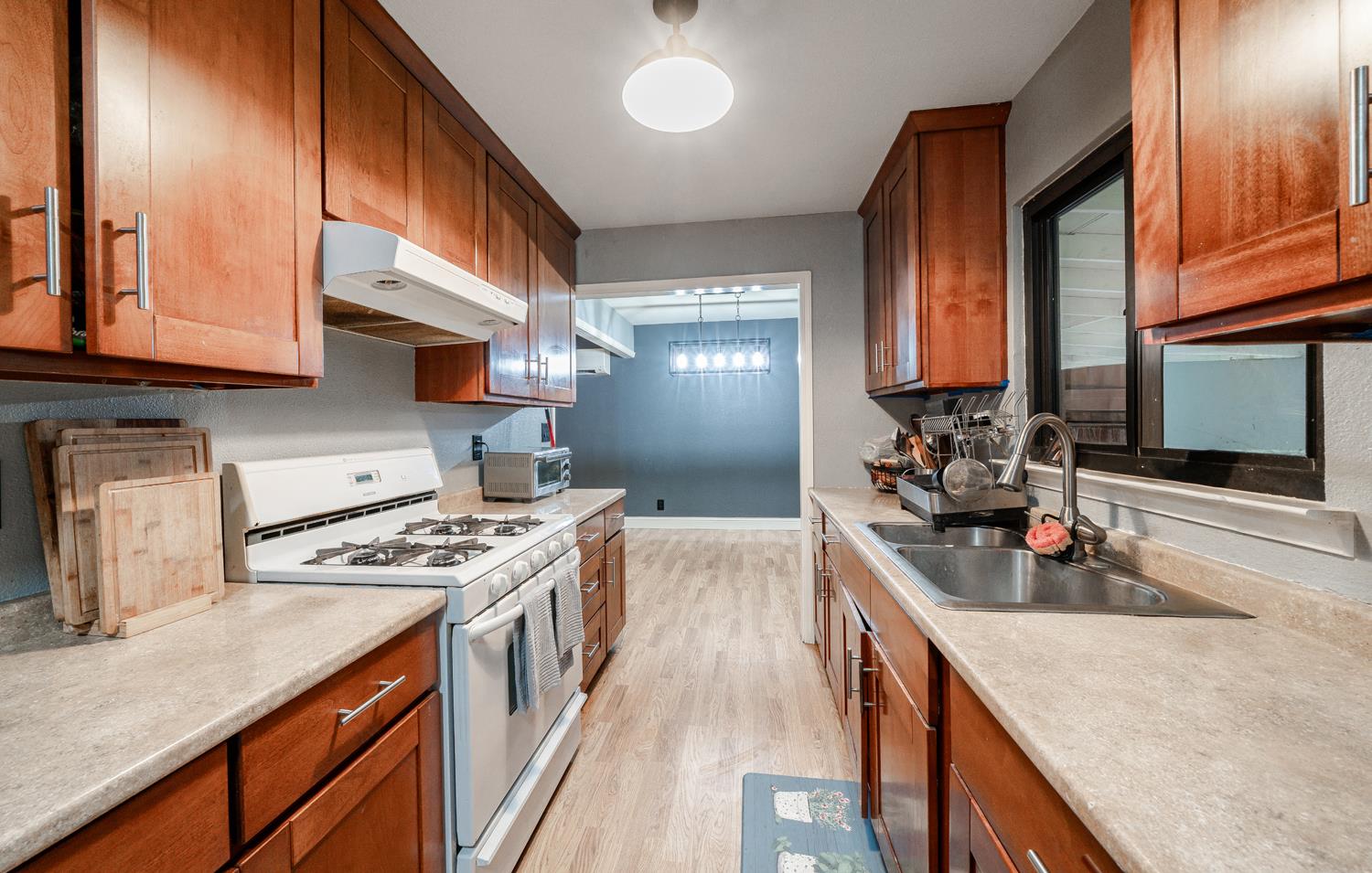 27152 Perkins Road Madera, CA 93637 - Photo 12 of 25 a kitchen with stainless steel appliances granite countertop a stove a sink dishwasher and cabinets with wooden floor
