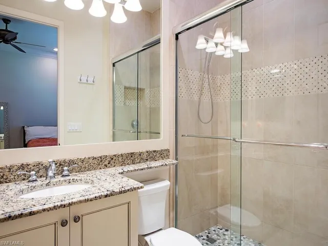 a bathroom with a granite countertop sink a toilet and shower