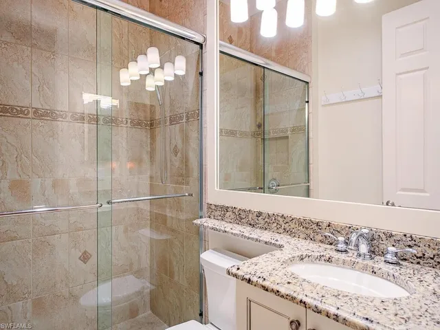 a bathroom with a granite countertop shower sink and mirror