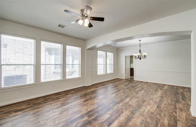 a view of an empty room with a window and a kitchen