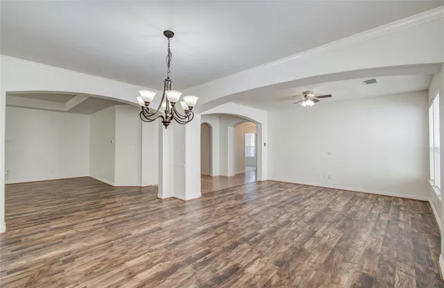 a view of a room with wooden floor chandelier and a ceiling fan