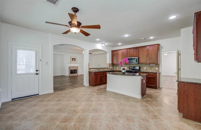 a kitchen with stainless steel appliances granite countertop a refrigerator a oven a sink with a dining table and chairs