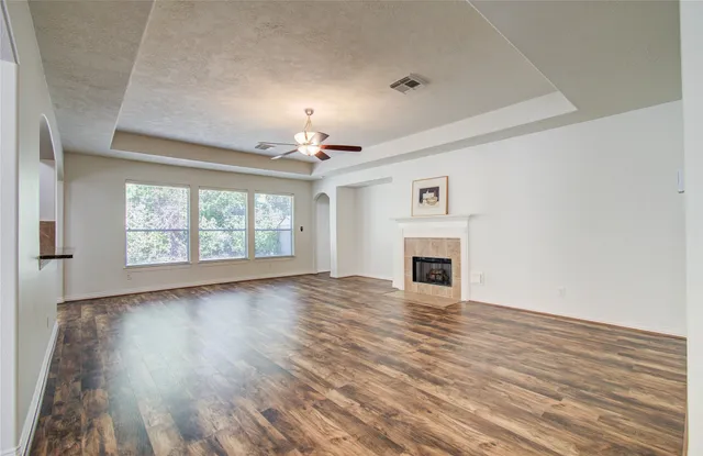 an empty room with wooden floor fireplace and windows