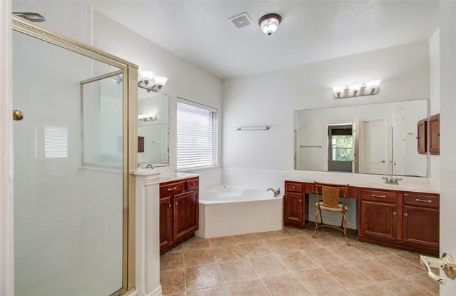 a spacious bathroom with a tub double sink and mirror