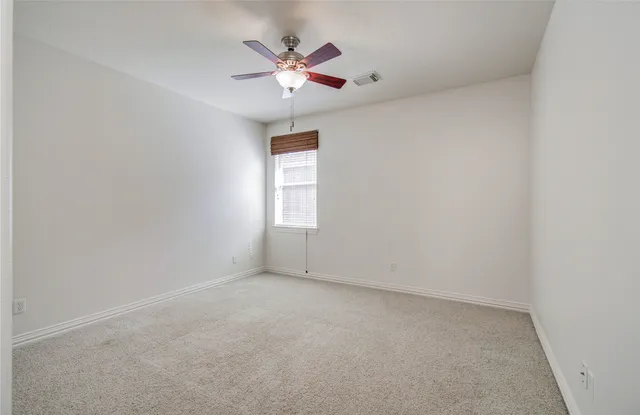 an empty room with a chandelier fan and windows