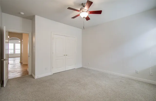 an empty room with closet and a chandelier fan