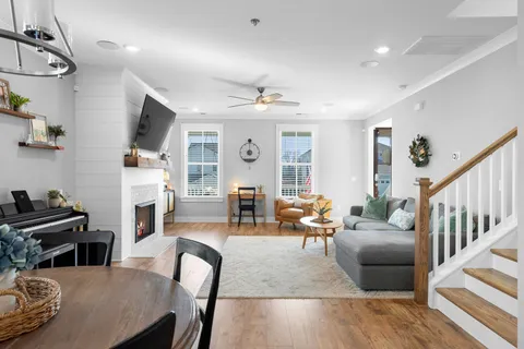a kitchen with stainless steel appliances kitchen island granite countertop a stove a refrigerator a sink a dining table and chairs with wooden floor
