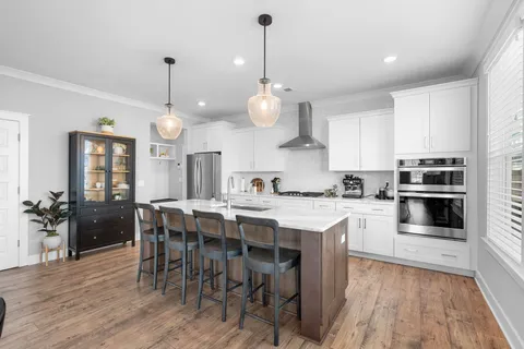 a kitchen with stainless steel appliances granite countertop a sink a stove and a wooden floors