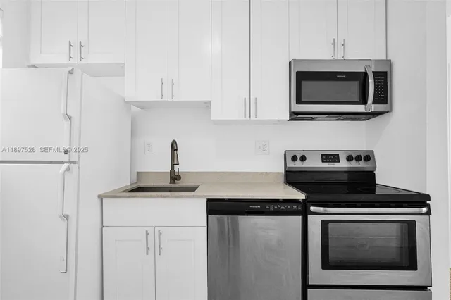 a kitchen with stainless steel appliances white cabinets and a stove a sink