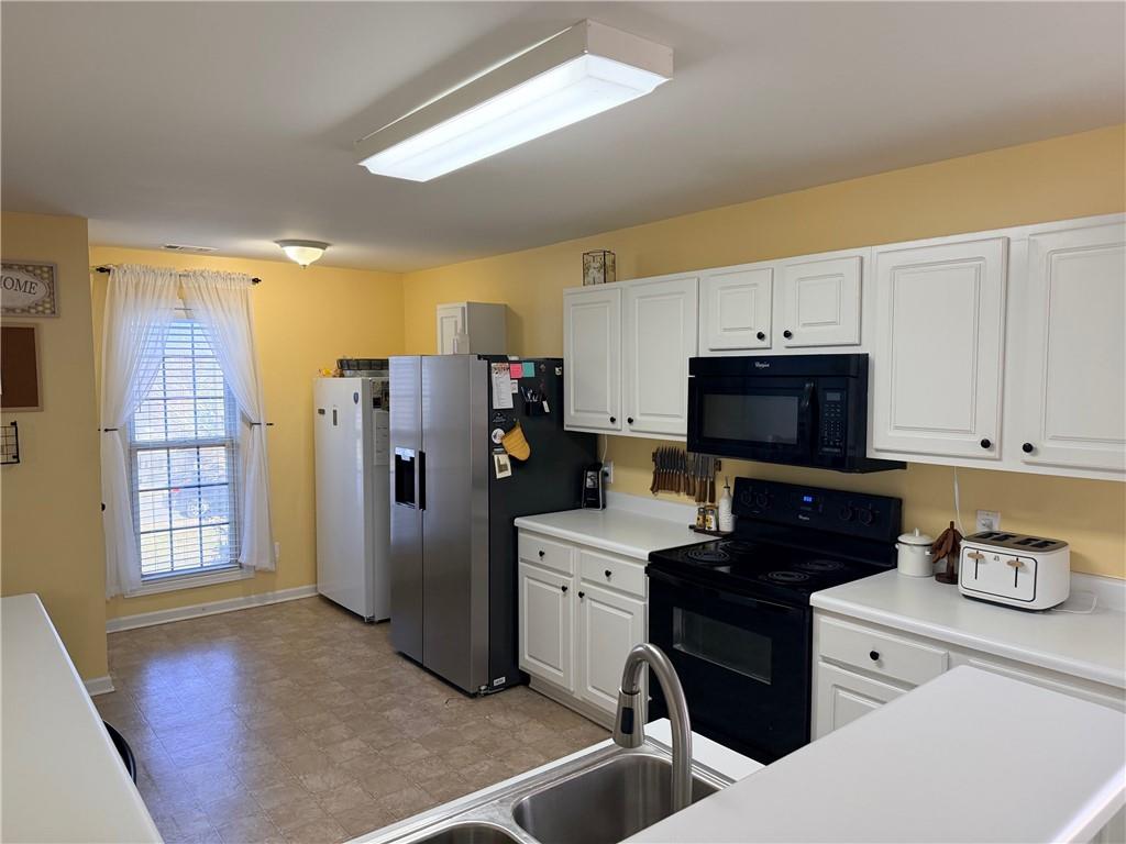 59 Indian Hills Drive Rydal, GA 30171 - Photo 9 of 35 a kitchen with stainless steel appliances a refrigerator a stove a sink dishwasher and white cabinets with wooden floor