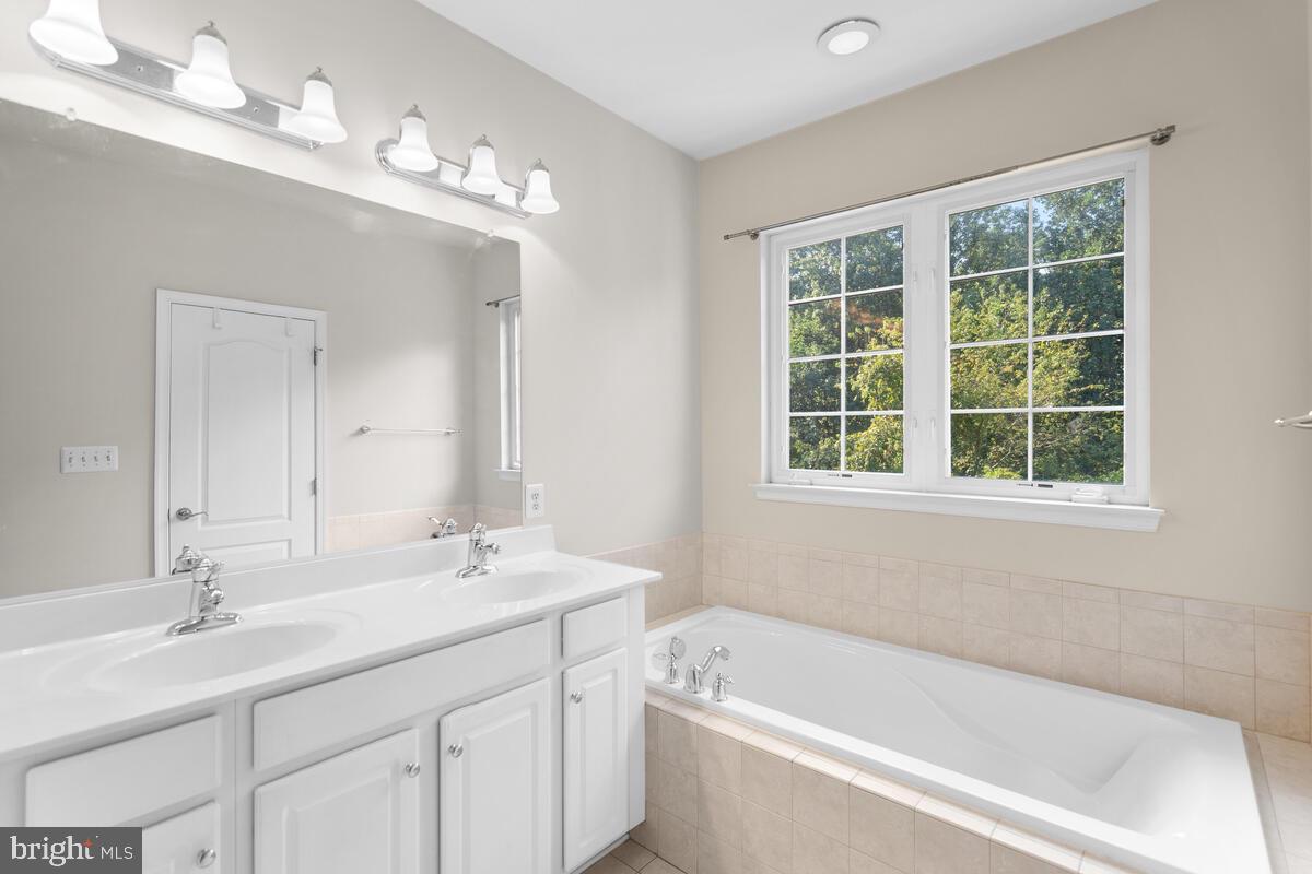13626 Dover Cliffs Place Germantown, MD 20874 - Photo 19 of 32 a bathroom with a tub a sink a window and a mirror