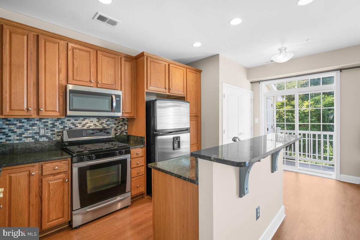 13626 Dover Cliffs Place Germantown, MD 20874 - Photo 4 of 32 a kitchen with stainless steel appliances granite countertop a stove a sink and a refrigerator