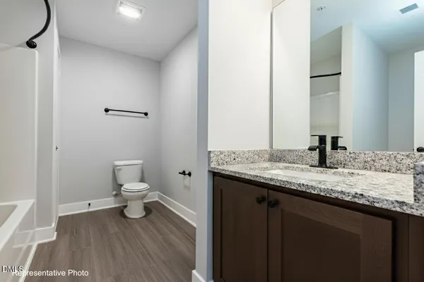 a bathroom with a granite countertop sink toilet and a mirror