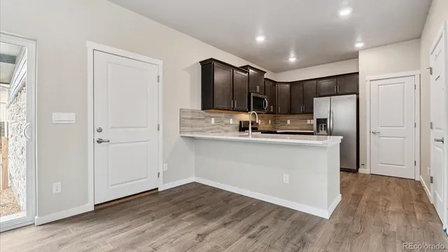 a kitchen with kitchen island stainless steel appliances a refrigerator cabinets and wooden floor