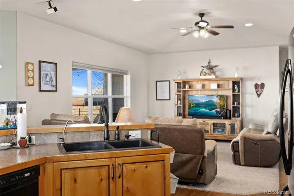 a living room with furniture a flat screen tv and kitchen view