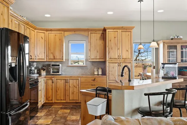 a kitchen with stainless steel appliances granite countertop a refrigerator a stove a sink dishwasher and white cabinets with wooden floor