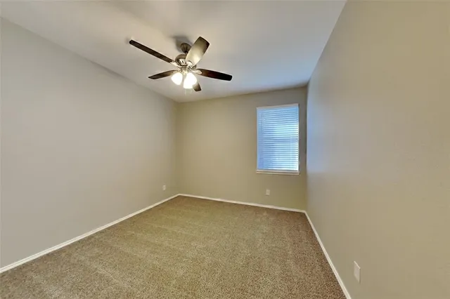 an empty room with a window and ceiling fan