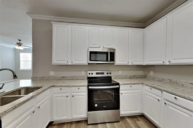 a kitchen with granite countertop white cabinets and stainless steel appliances