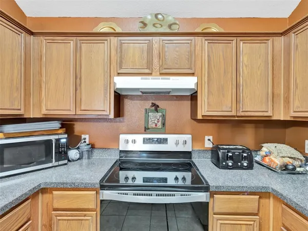 a kitchen with granite countertop a stove a sink and dishwasher wooden cabinets