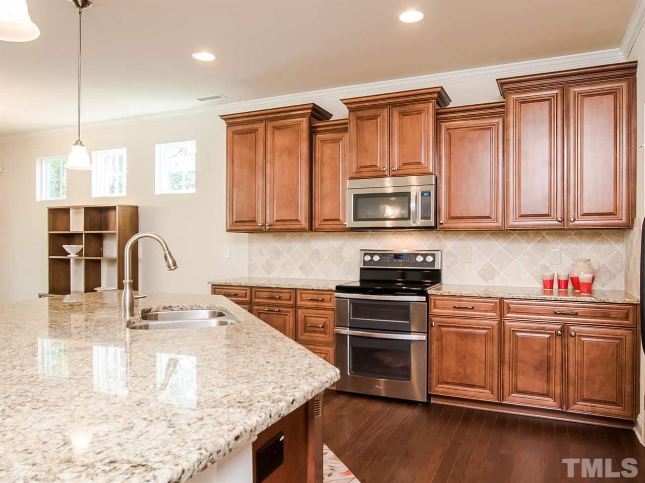 6508 Ridgemount Street Wake Forest, NC 27587 - Photo 14 of 24 Beautiful upgraded "waterfall" style cabinets with dovetail drawers and soft closure doors, hidden trash bin and pull down sink drawer. Tile back splash and granite counters turn this kitchen into an exquisite focal point of this grand space.
