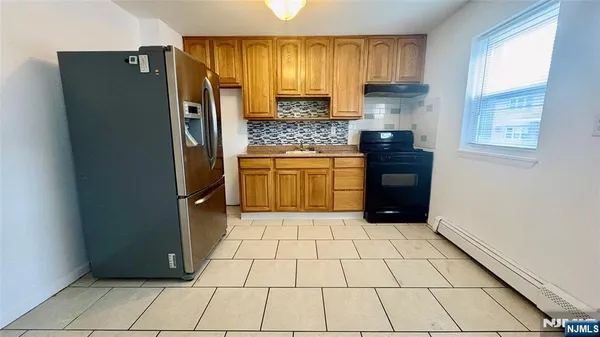 a kitchen with stainless steel appliances granite countertop a refrigerator a stove a sink and a window