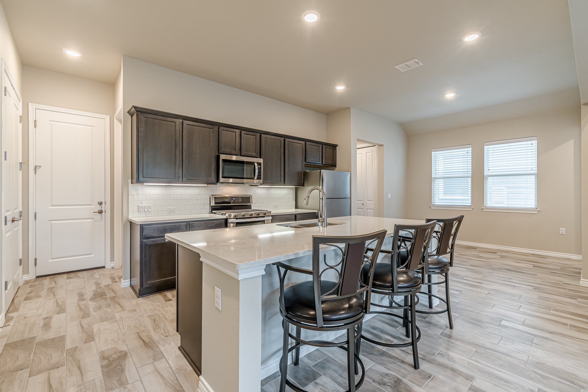 108 Lafitte Drive, Unit 102 San Marcos, TX 78666 - Photo 12 of 27 Kitchen featuring appliances with stainless steel finishes, a kitchen island with sink, a breakfast bar area, dark brown cabinets, and tasteful backsplash