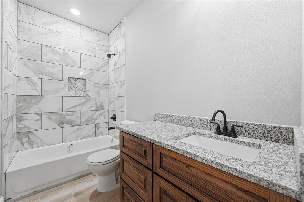 308 Lewis Street Cleburne, TX 76031 - Photo 15 of 20 a bathroom with a granite countertop bathtub sink vanity mirror and toilet