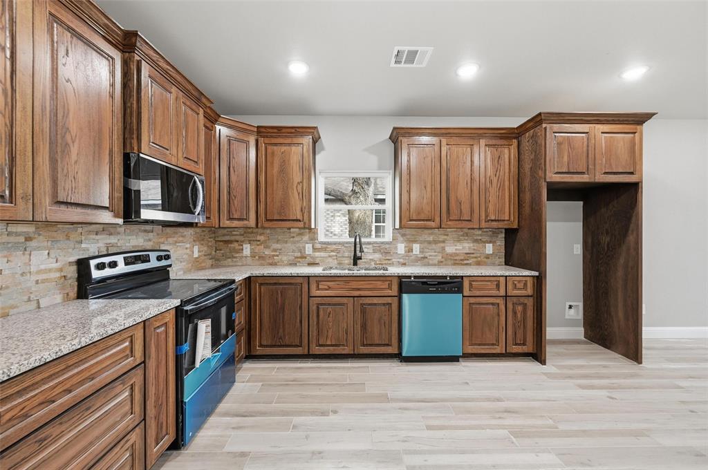 308 Lewis Street Cleburne, TX 76031 - Photo 6 of 20 a kitchen with stainless steel appliances granite countertop wooden cabinets a stove top oven a sink and dishwasher