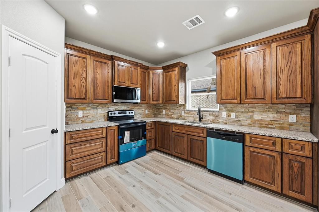 308 Lewis Street Cleburne, TX 76031 - Photo 8 of 20 a kitchen with stainless steel appliances granite countertop wooden cabinets a stove top oven a sink and dishwasher with wooden floor