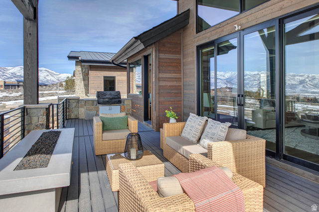 1282 Chimney Rock Road, Unit 344 Heber City, UT 84032 - Photo 16 of 55 Expansive exterior deck featuring a built-in fire pit, stone-clad outdoor kitchen with grill, and large sliding glass doors