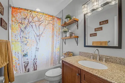 a bathroom with a granite countertop sink a toilet and shower curtain
