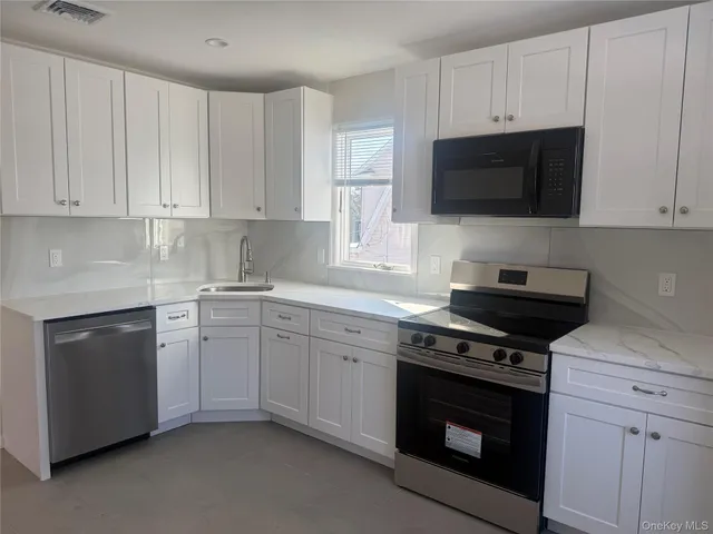 a kitchen with stainless steel appliances granite countertop grey cabinets a stove a sink and dishwasher