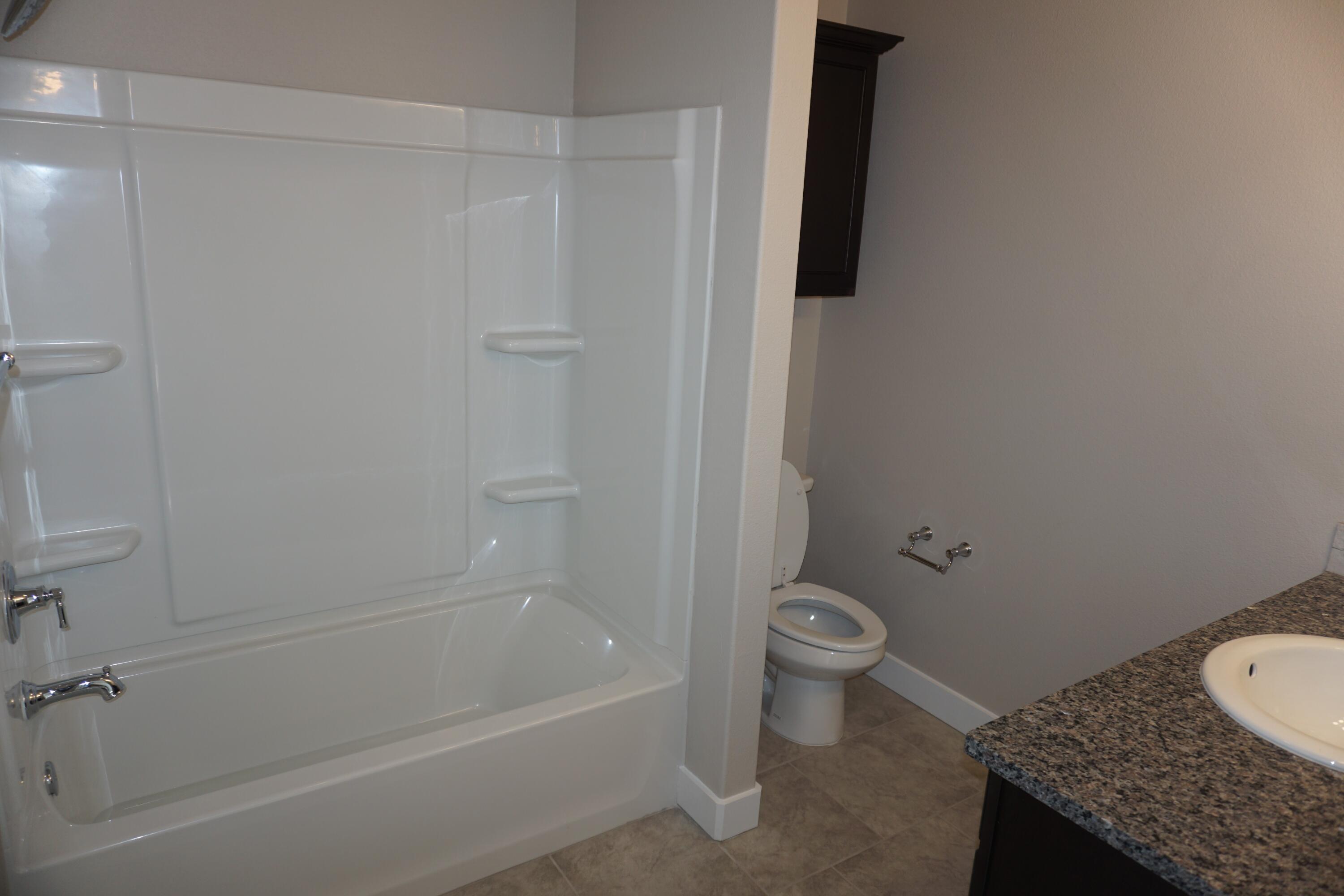 7517 31st Street Lubbock, TX 79407 - Photo 11 of 14 a bathroom with a granite countertop toilet and a sink