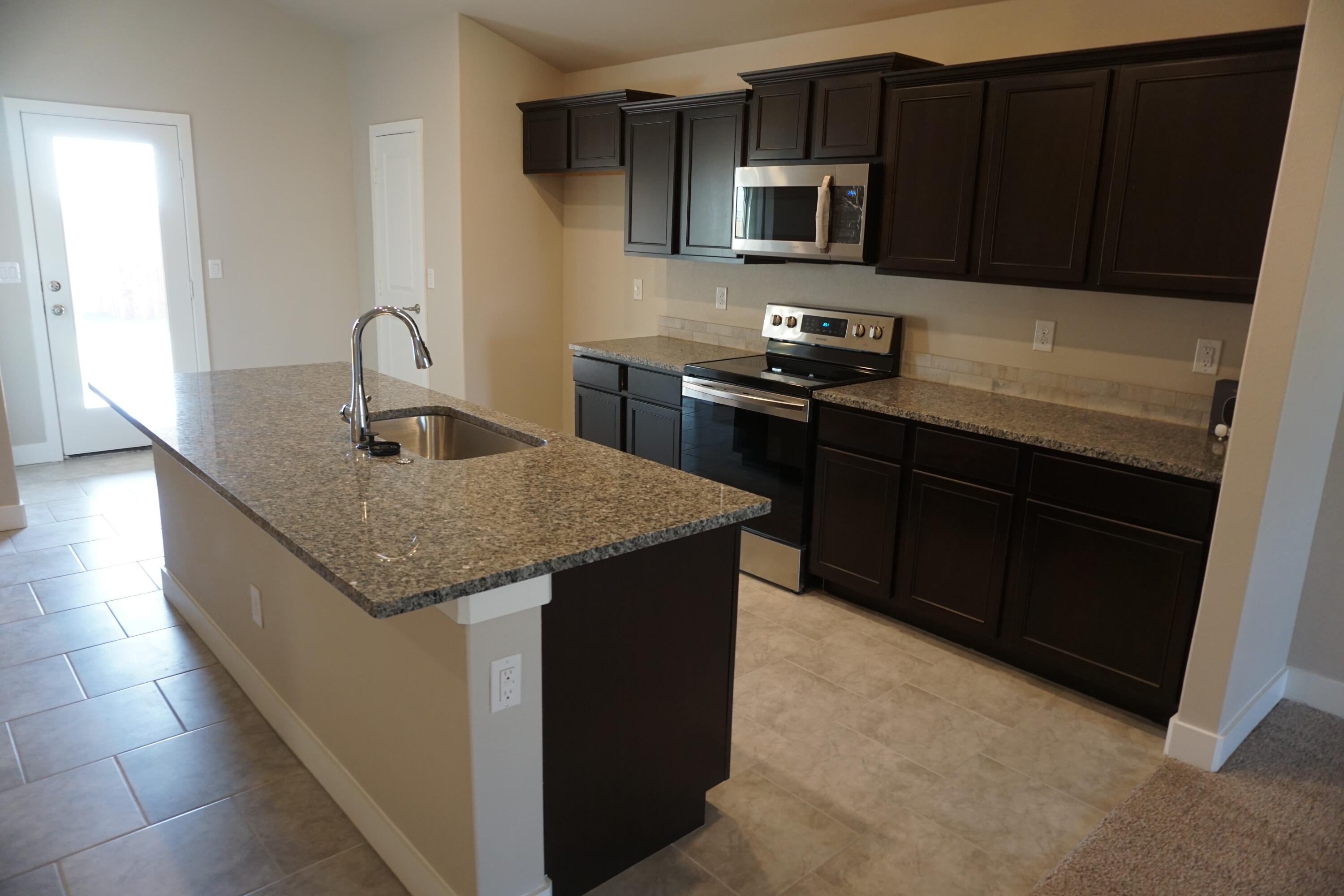 7517 31st Street Lubbock, TX 79407 - Photo 3 of 14 a kitchen with granite countertop stainless steel appliances and wooden cabinets