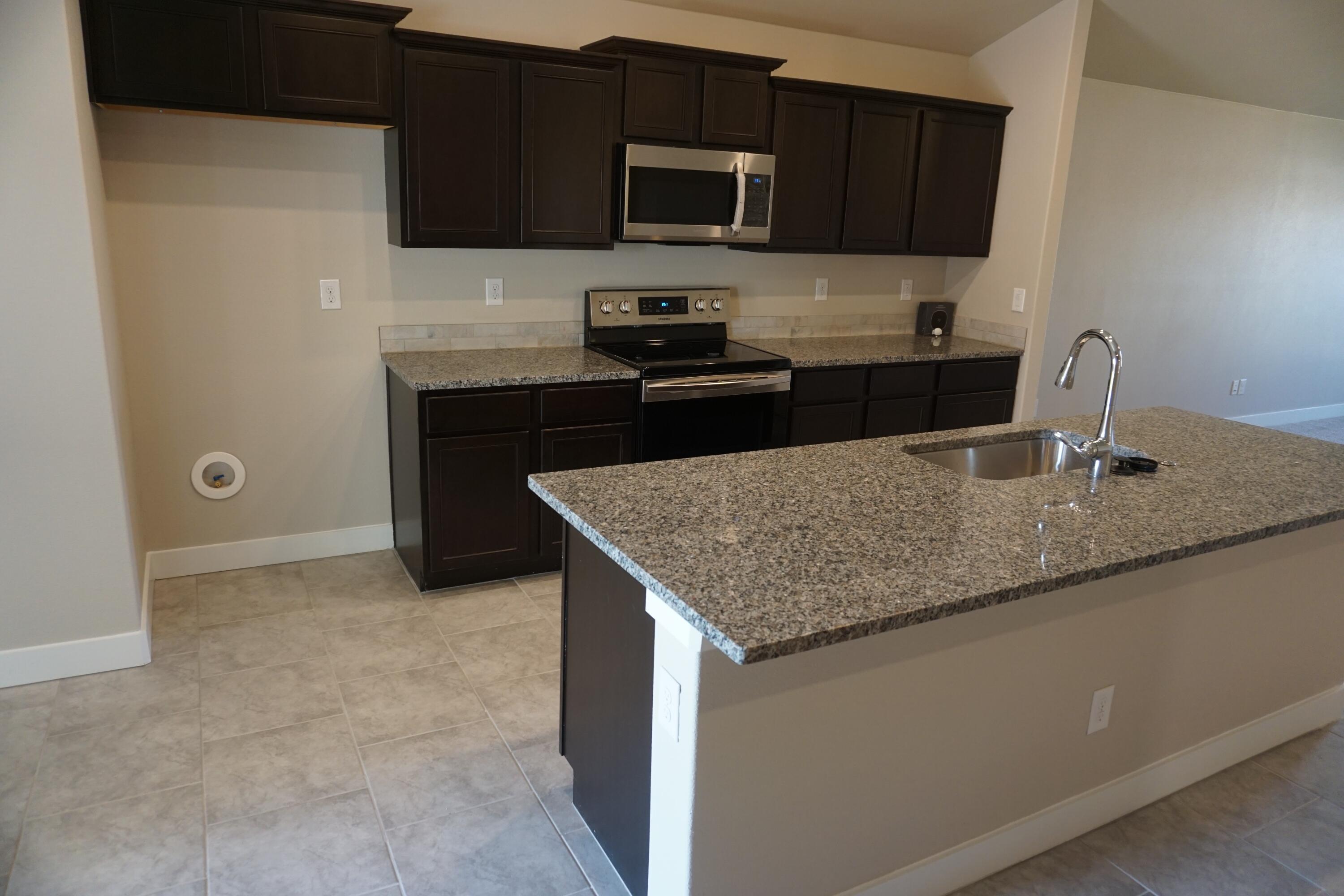 7517 31st Street Lubbock, TX 79407 - Photo 4 of 14 a kitchen with stainless steel appliances granite countertop a sink stove and microwave