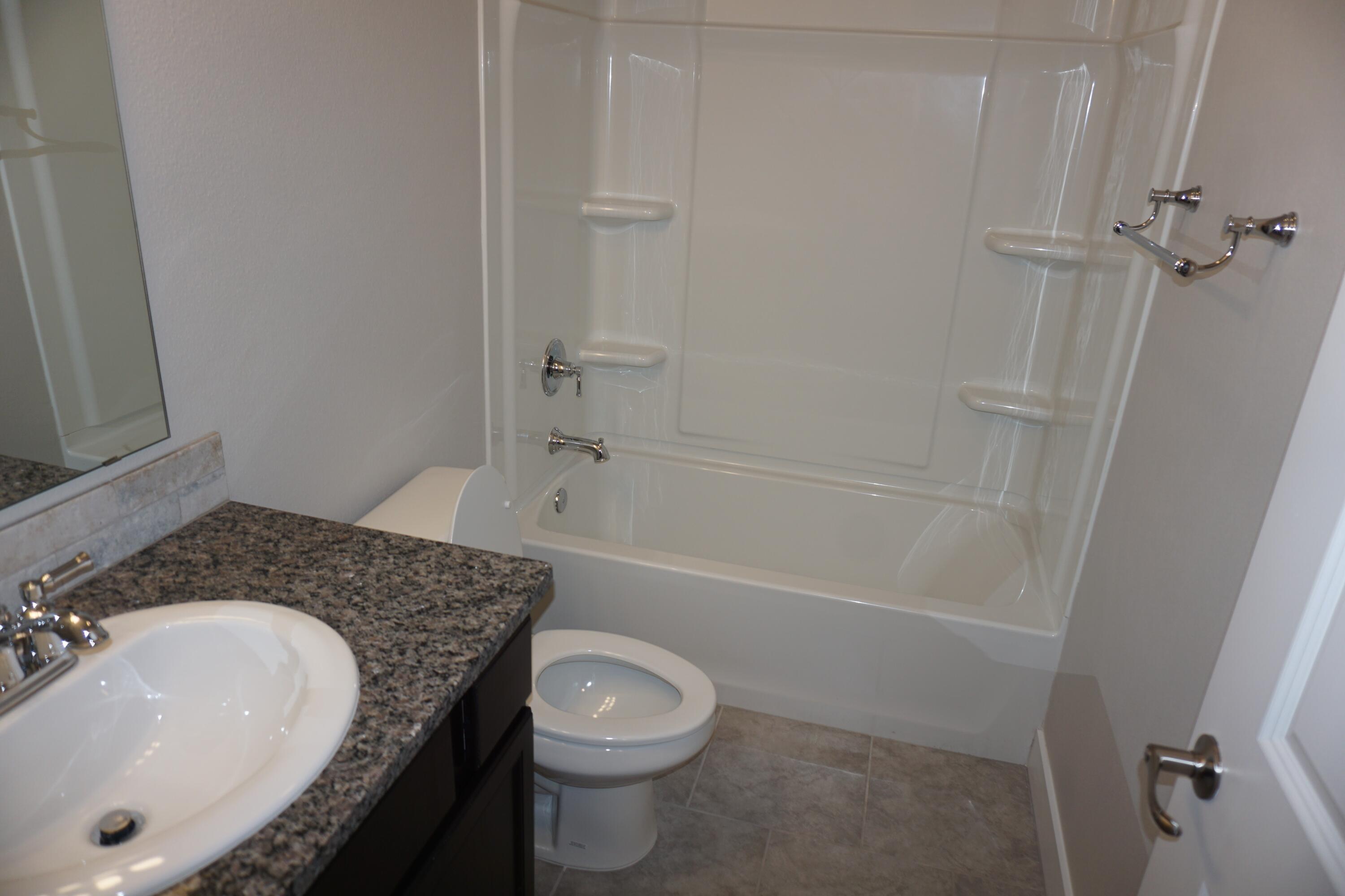 7517 31st Street Lubbock, TX 79407 - Photo 9 of 14 a bathroom with a granite countertop sink toilet and shower