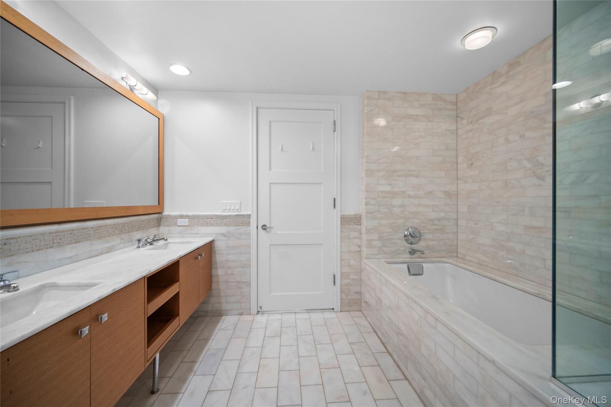 1 Renaissance Square, Unit 10C White Plains, NY 10601 - Photo 17 of 28 Bathroom featuring tile walls, double vanity, a garden tub, and a wainscoted wall