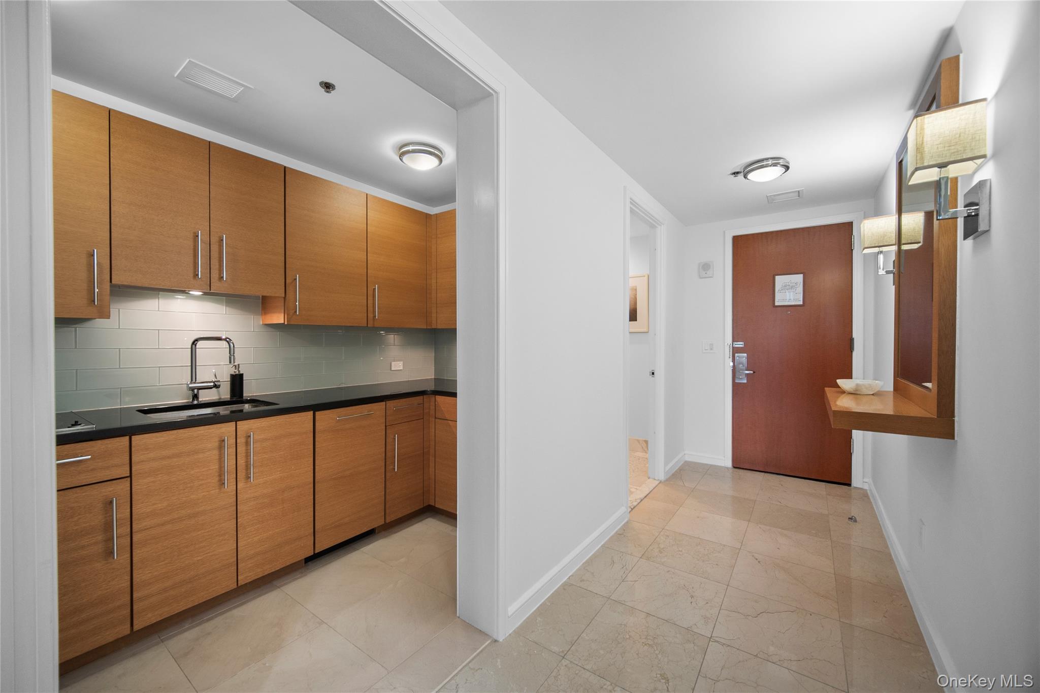 1 Renaissance Square, Unit 10C White Plains, NY 10601 - Photo 6 of 28 Kitchen featuring a sink, baseboards, brown cabinets, dark countertops, and decorative backsplash