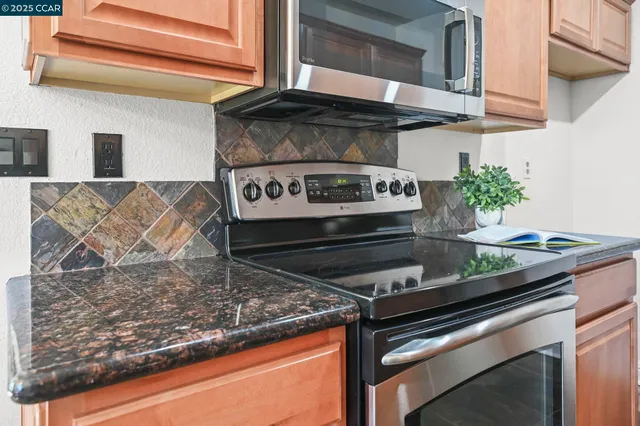 a kitchen with stainless steel appliances granite countertop a stove top oven a sink a dining table and chairs with wooden floor