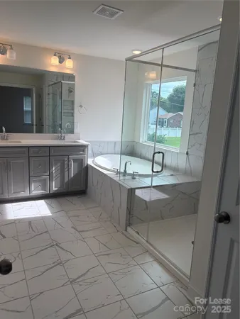 a spacious bathroom with a tub a sink and mirror